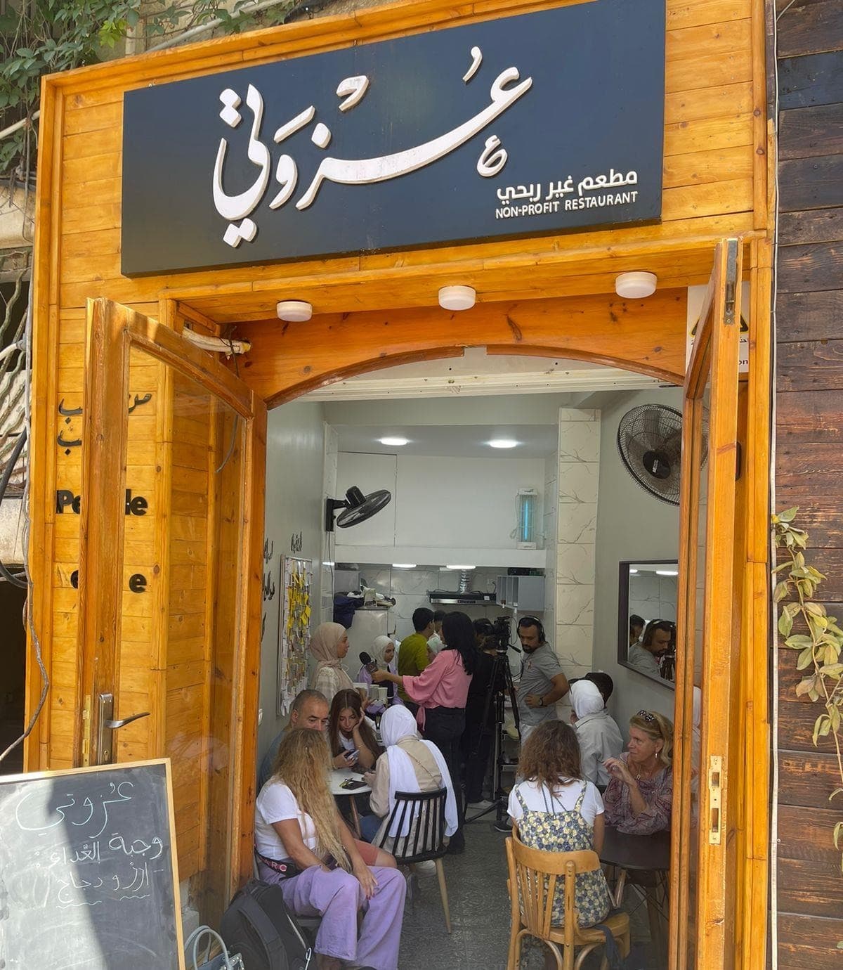 مطعم عزوتي في عمّان، الباب الخشبي مفتوح والمعزومون على الطاولات