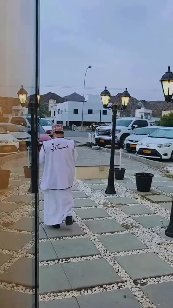 متطوعو عزوتي بصدرياتهم البيضاء أمام فرع سمائل وقت المغرب، والجبال خلفهم